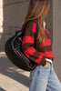 Bottega Veneta Small Jodie Black Intrecciato — lifestyle photo: worn over the shoulder by its knotted top handle, styled with a striped brown-and-red sweater and light-wash wide-leg jeans.
