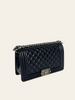 Chanel Boy Medium Black Lambskin — three-quarter angle view showing the bag's structured boxy silhouette and full chain strap.