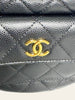 Chanel Polly Pocket Hobo Black Caviar — detail: close-up of the gold CC clasp on the front pocket, showing the caviar leather texture.