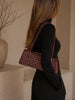 Goyard Bonbonnière Burgundy Goyardine — lifestyle photo: worn on the shoulder with a black turtleneck, showing the bag's silhouette and dual thin straps.
