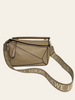Loewe Anagram Strap in Jacquard and Calfskin Sand Gold — lifestyle photo: shown attached to the Loewe Small Puzzle bag in sand calfskin.
