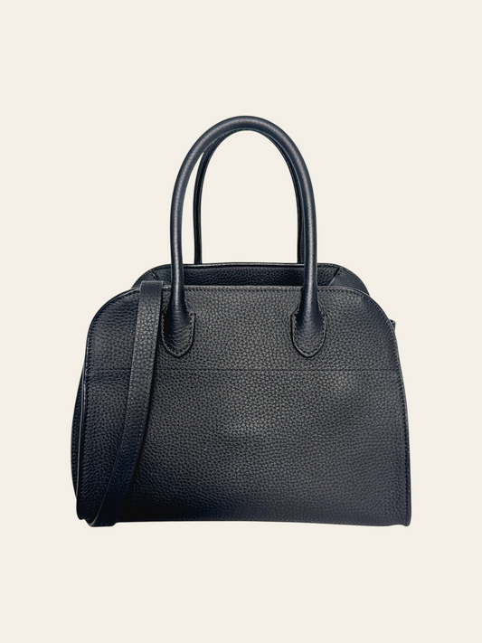The Row Soft Margaux 10 Black Grained Calfskin. Front view of a structured black grained calfskin bag with a boxy, dome-topped bowling-bag silhouette, double rolled top handles, and an adjustable/removable shoulder strap at the side.