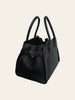 The Row Soft Margaux 10 Black Grained Calfskin. Angled side/back view of the black grained calfskin bag showing the dome silhouette, double rolled handles, and a small buckled strap detail at the front seam.