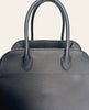 The Row Soft Margaux 10 Black Grained Calfskin — detail: close-up of the black grained calfskin bag's top handles and dome-shaped silhouette.